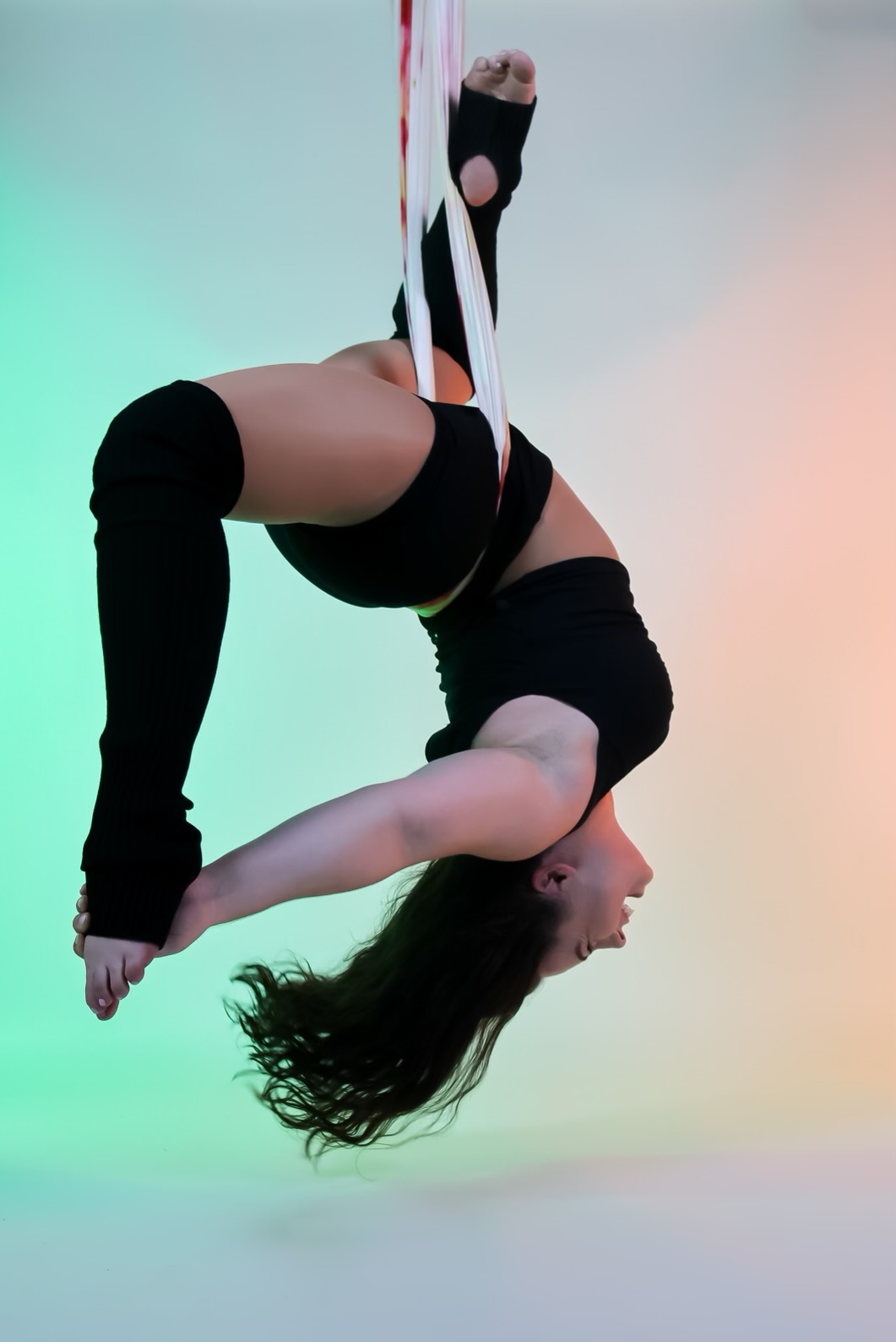Student hanging upside down in a white aerial yoga hammock during an aerial yoga class at Flexibility in Flight